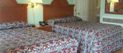 Habitación de hotel con dos camas, cada una con ropa de cama estampada. Se observan mesitas de noche con lámparas, una puerta y un radiador.