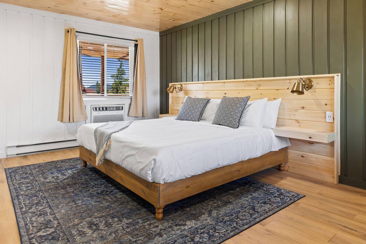 A bedroom with a wooden bed, a window with curtains, and a green wall.