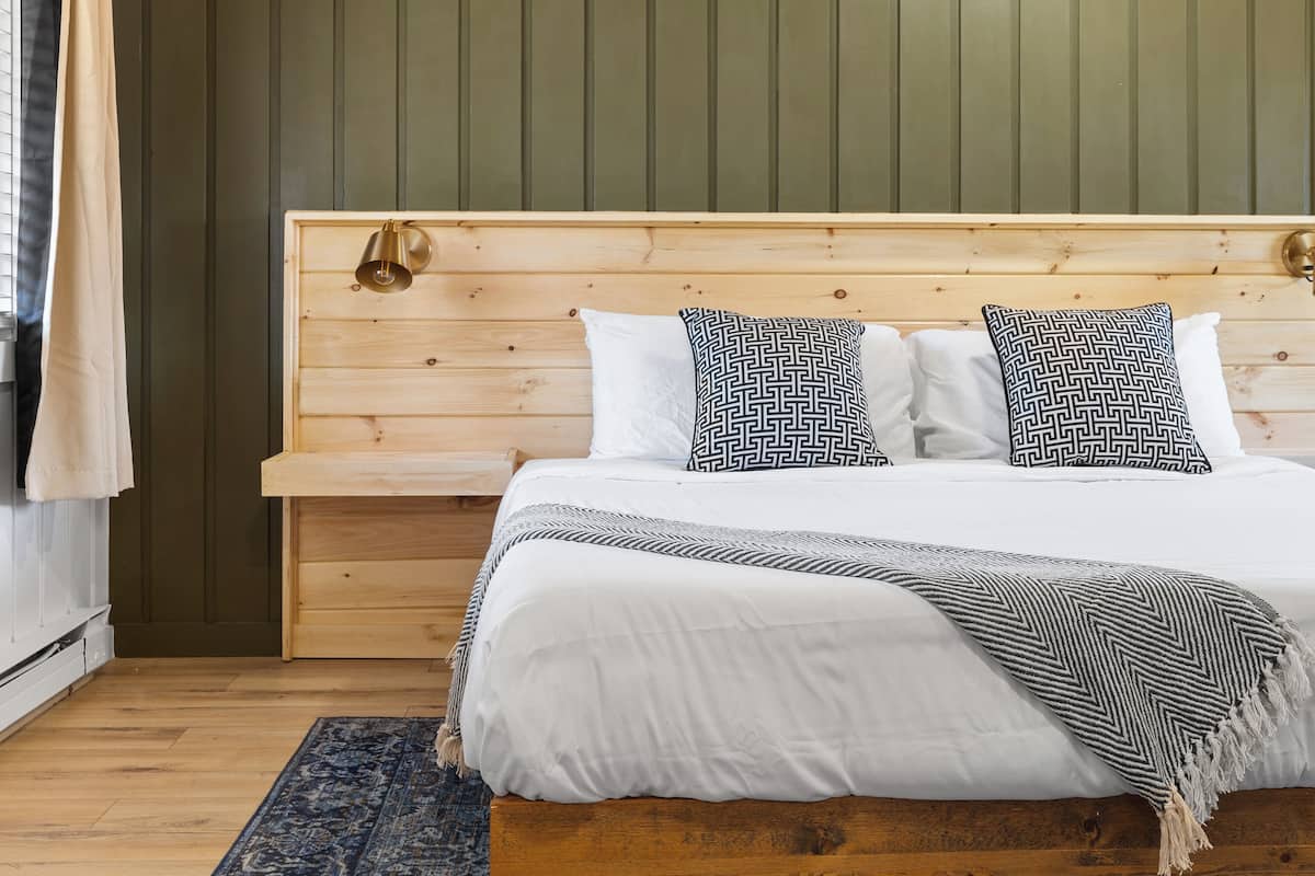 A bed with a wooden headboard, white bedding, and patterned pillows.