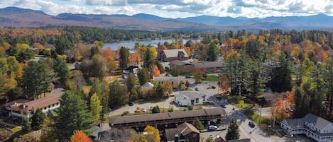 An aerial view of a residential area with houses, a church, and a lake surrounded by mountains.
