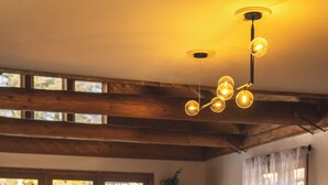 A modern kitchen with a wooden bar area, large windows, and a hanging light fixture. - The Boha Hotel (Lake Placid)