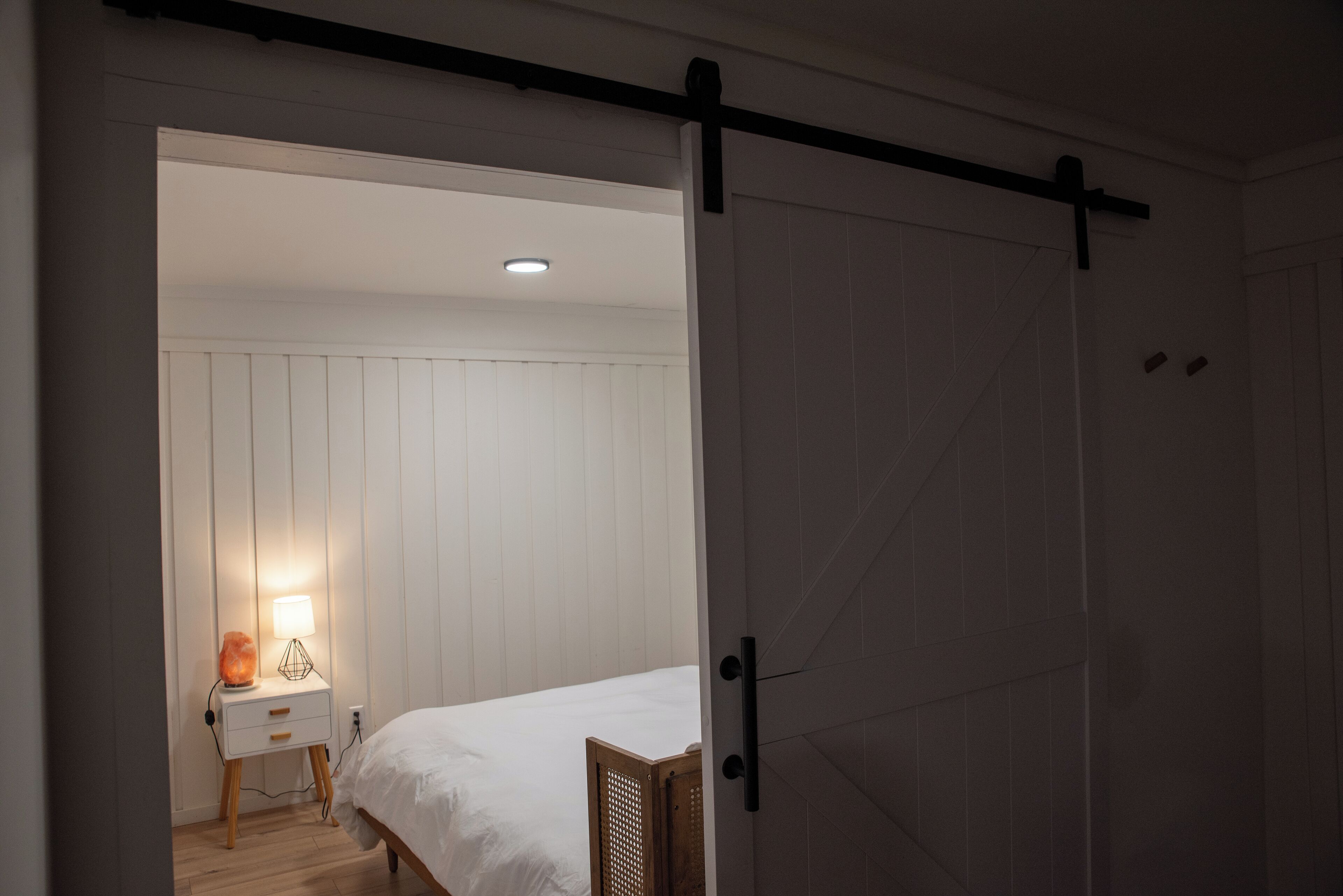 Une chambre à coucher avec un lit, une table de chevet avec une lampe et une porte coulissante de style grange.