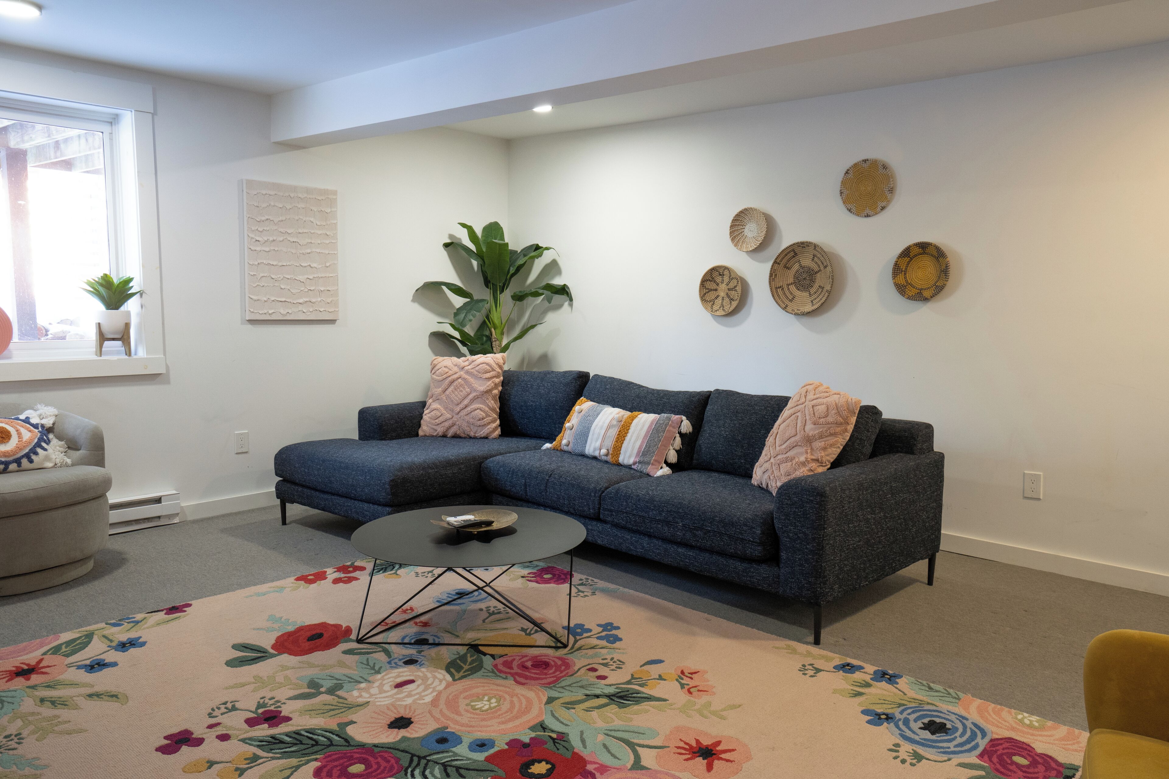 Una sala de estar con un sofá modular, una mesa de centro, una planta en maceta y decoración en la pared.