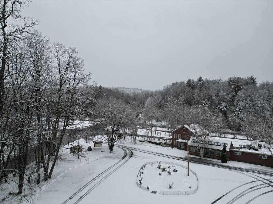 A snow-covered landscape with a road, a circular park area, and a red building with a gabled roof.