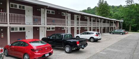 Ein Motel mit einer Reihe von Zimmern, jedes mit einem Balkon. Vor dem Haus sind mehrere Autos geparkt.