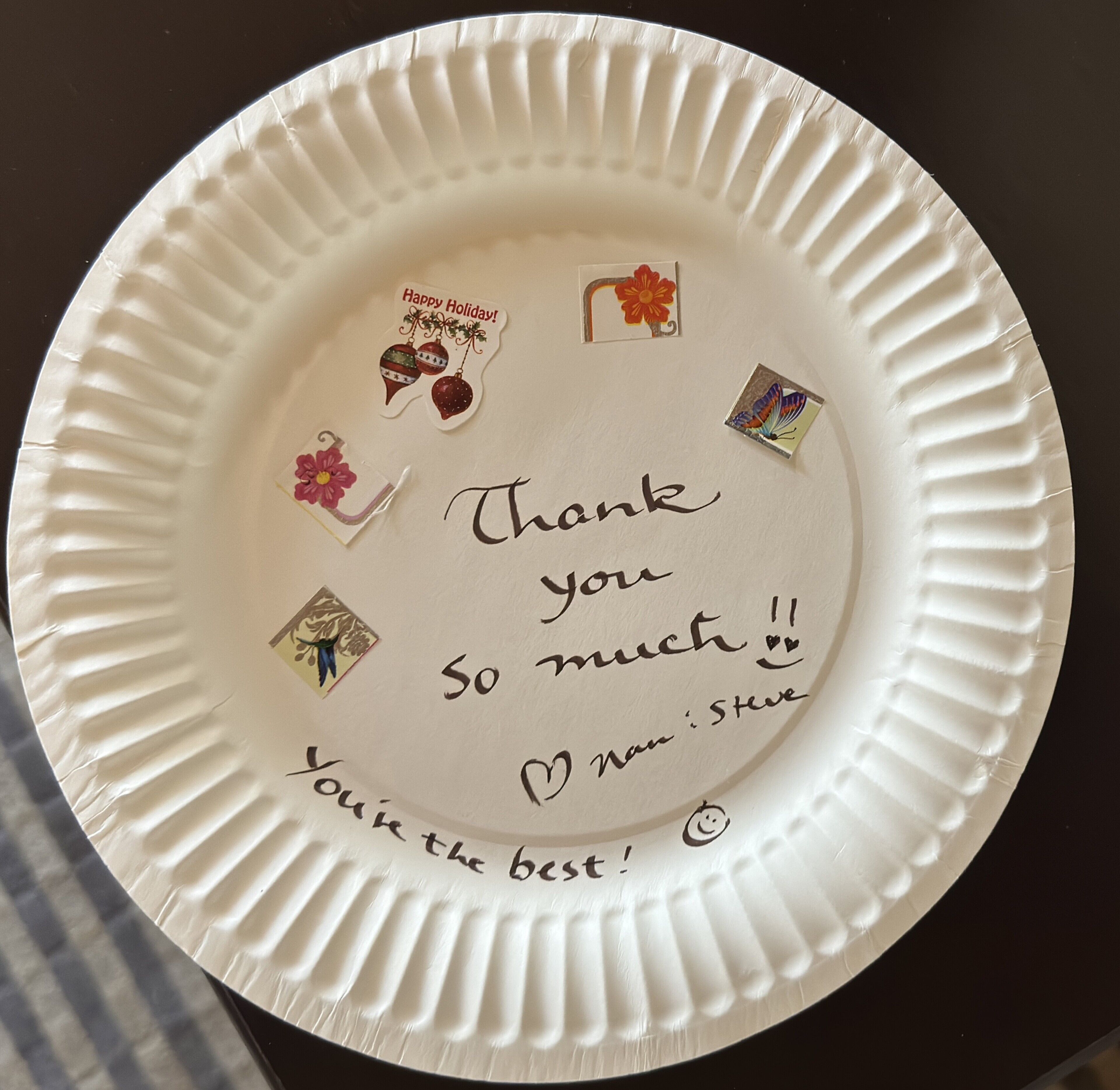 Un plato de papel blanco con un mensaje manuscrito de agradecimiento y un pequeño regalo.