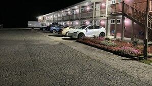 Un motel con estacionamiento, un corredor cubierto y una escalera que lleva a la entrada.