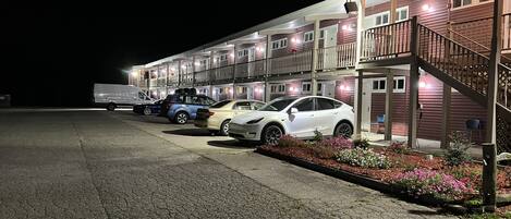 A motel with a parking lot, a covered walkway, and a staircase leading to the entrance.