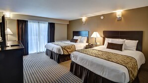 Habitación de hotel con dos camas, un escritorio y una televisión.