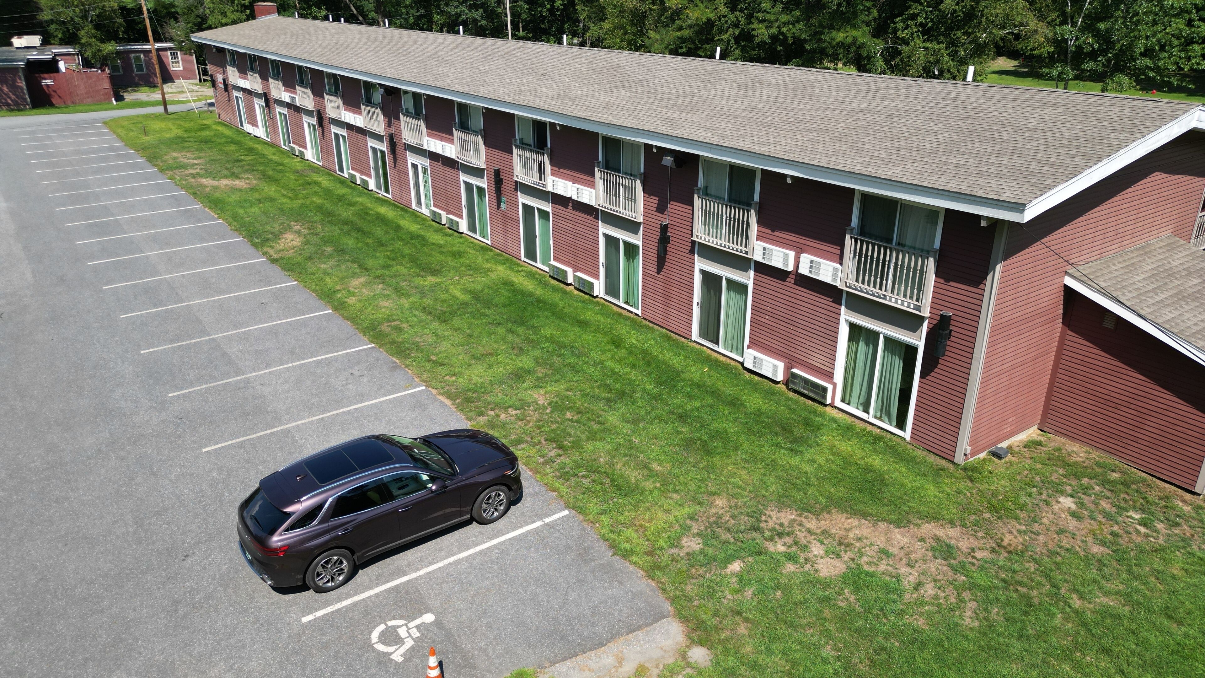 A multi-story motel with a parking lot and a single car parked.