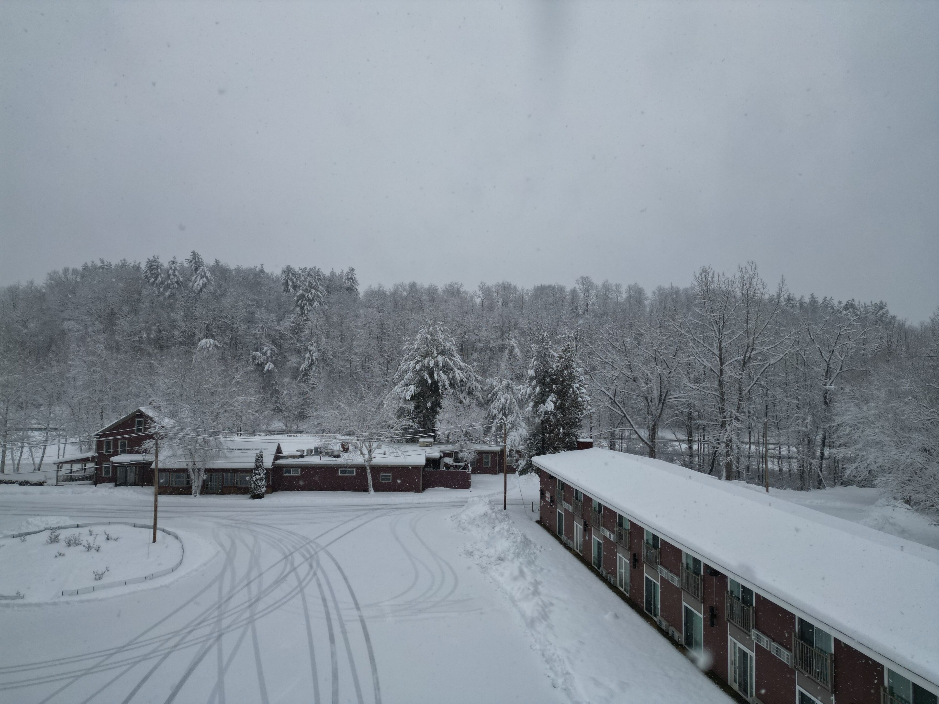 A snow-covered landscape with a building and trees.