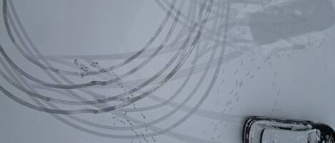 A car parked on a snow-covered road with tire tracks.