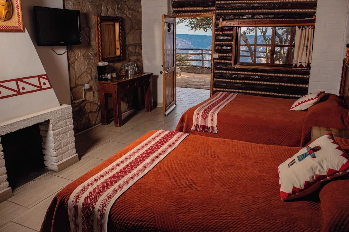 Une chambre confortable avec deux lits, une cheminée, une télévision et une vue sur les montagnes.