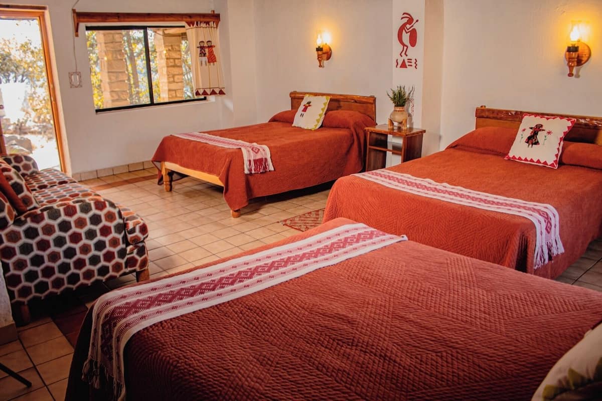 Une chambre d’hôtel avec deux lits, un canapé et une fenêtre avec des rideaux.