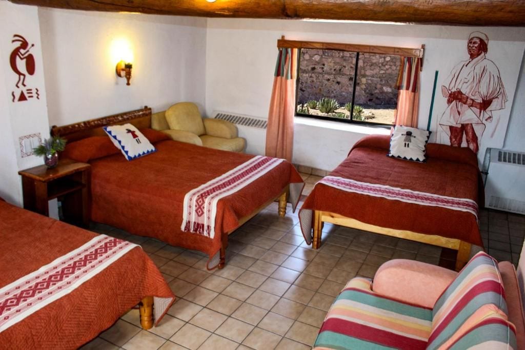 A hotel room with two beds, a sofa, a window with a view, and a mural on the wall.