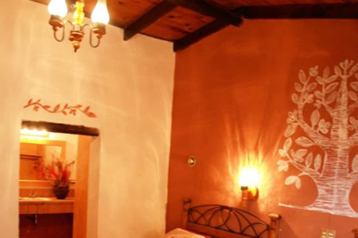 Une chambre avec deux lits, un plafond en bois et un mur orné d’une fresque représentant un arbre.