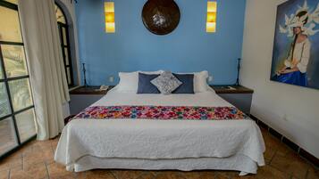 Een slaapkamer met een groot bed, een blauwe muur, een decoratief bord en een schilderij.