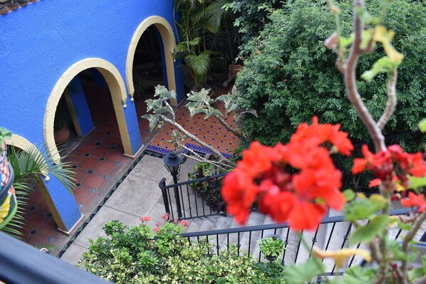 Un patio con un muro azul, arcos y un suelo de baldosas.