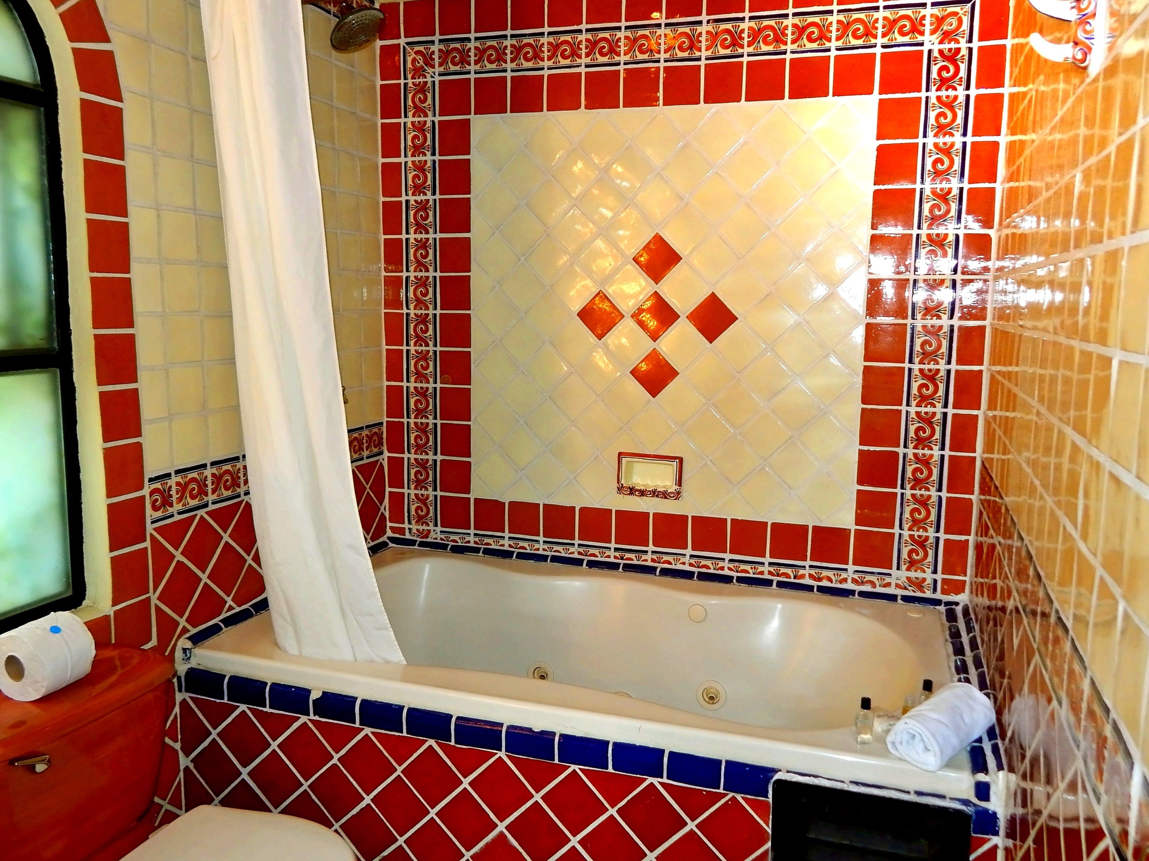 A bathroom with a bathtub, a toilet, and a shower curtain.