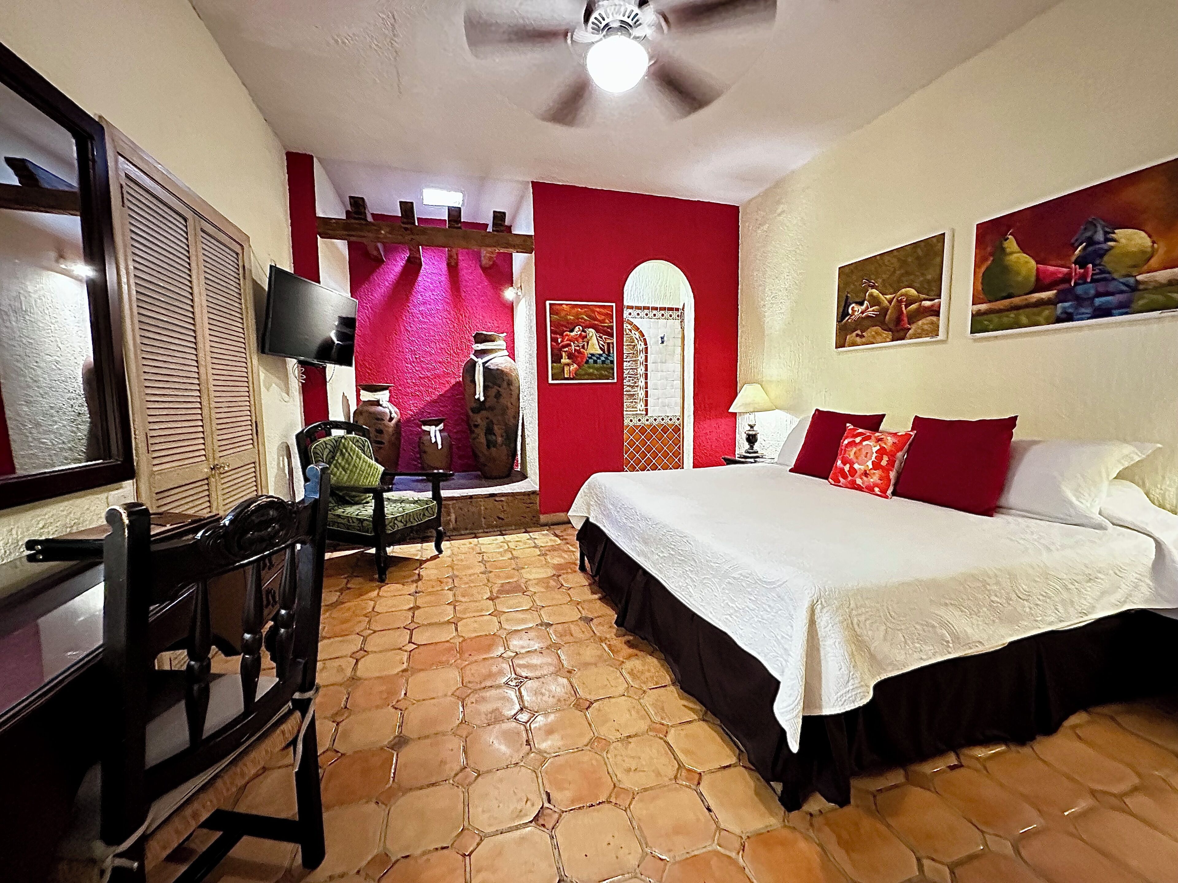 A bedroom with a bed, a chair, a desk, and a TV.