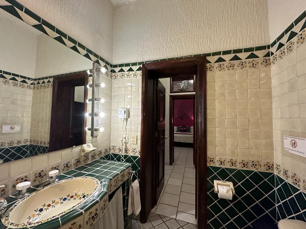 A bathroom with a large mirror, a sink, and a toilet.