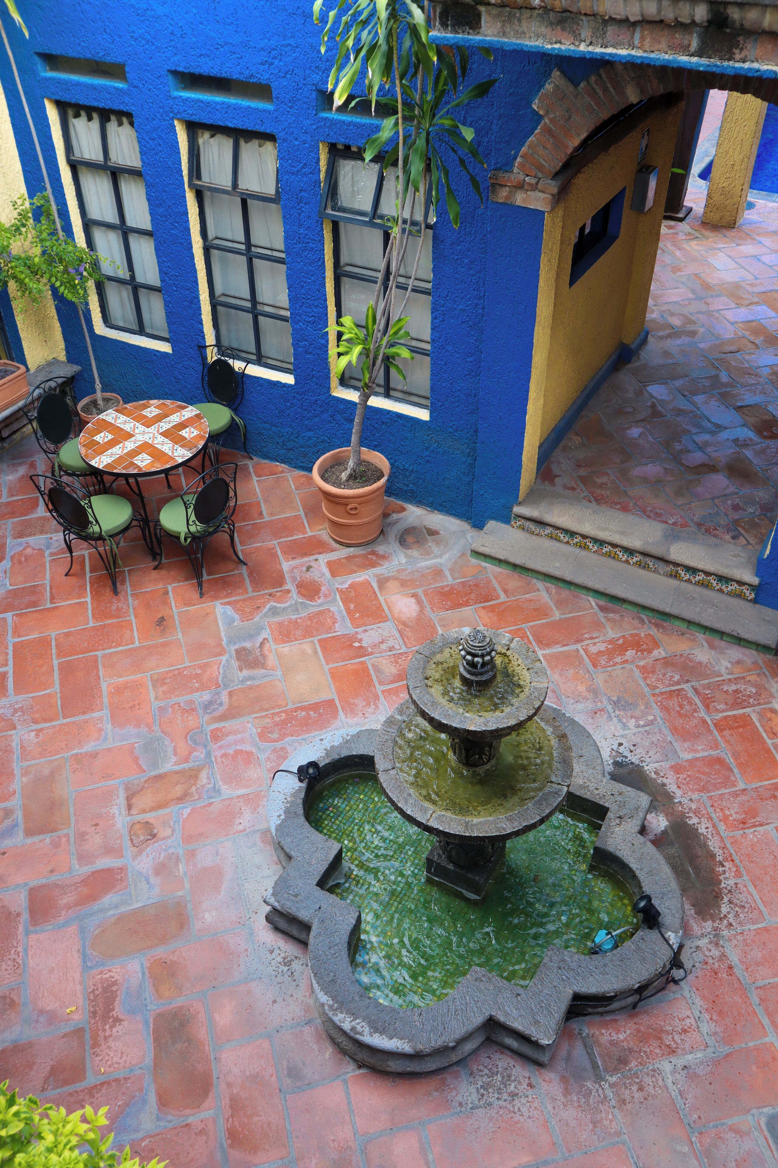 A courtyard with a fountain, a table with chairs, and a potted plant.