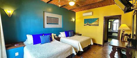 Una habitación con dos camas, techo de ladrillo, un cuadro y suelo de baldosas.