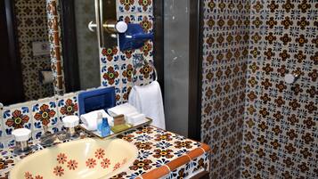 Un baño con salpicadero de azulejos florales, un lavabo con espejo y un perchero para toallas.