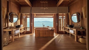 A wooden spa room with a large wooden bathtub, wooden benches, and two mirrors.