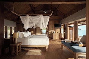 A wooden cabin bedroom with a bed, bedside table, and a view of the sea.