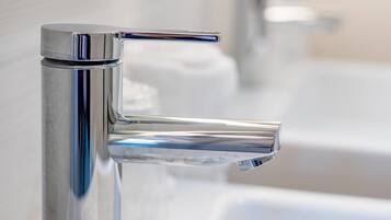 Een moderne badkamer met een chromen kraan, een glazen douchecabine en een witte wasbak.