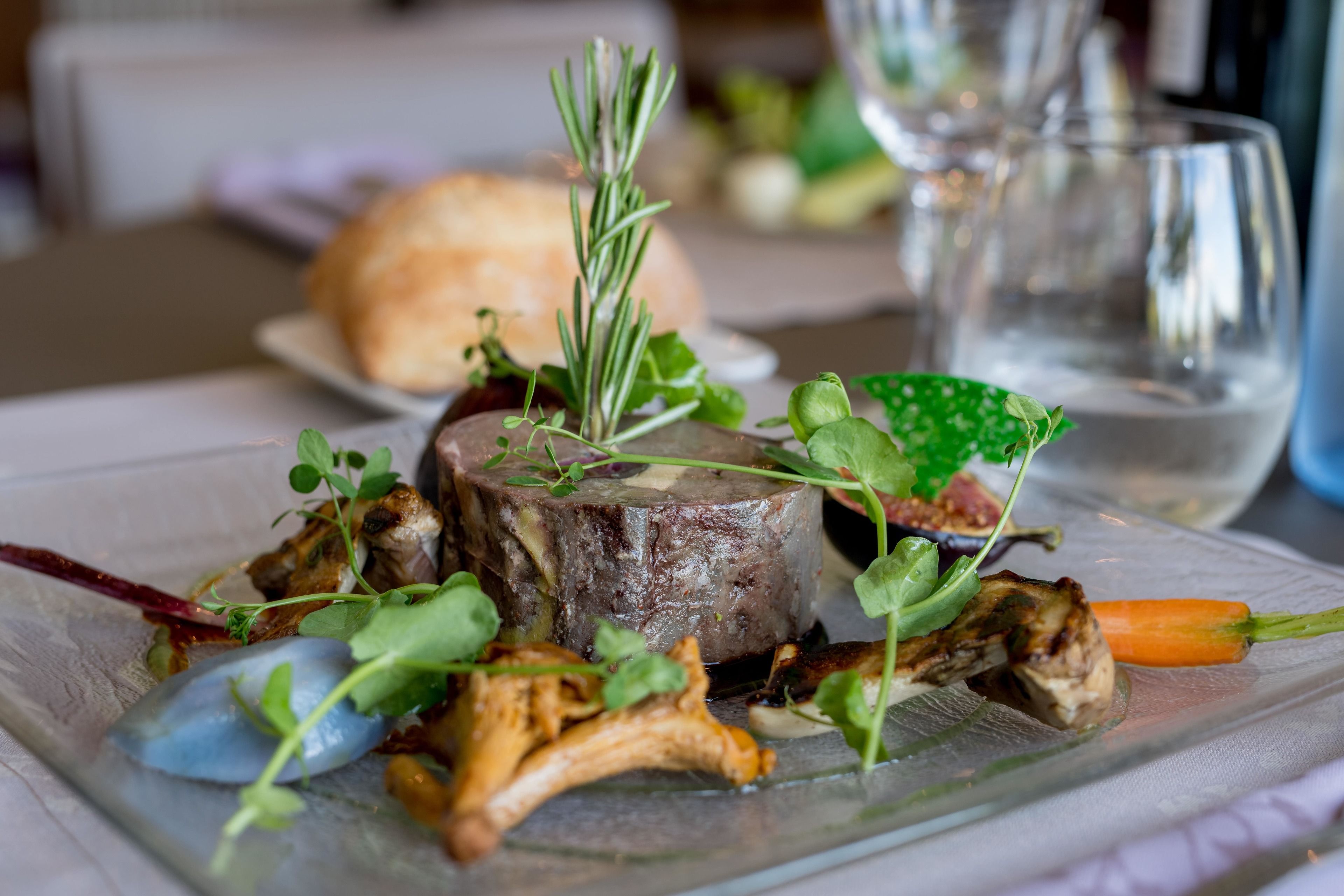 A plate of food with a steak, vegetables, and a sprig of rosemary.