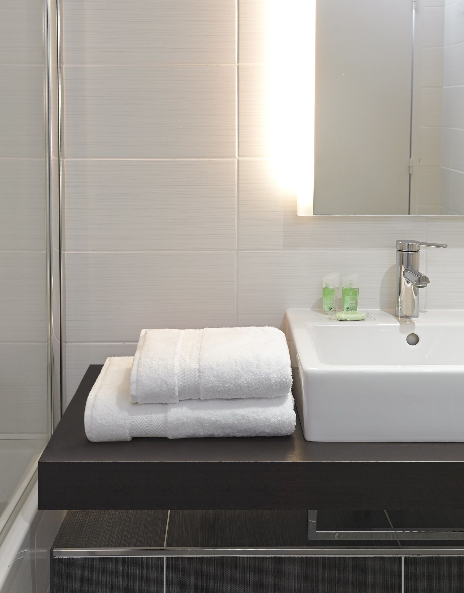A bathroom with a white sink, a mirror, and a towel on the counter.