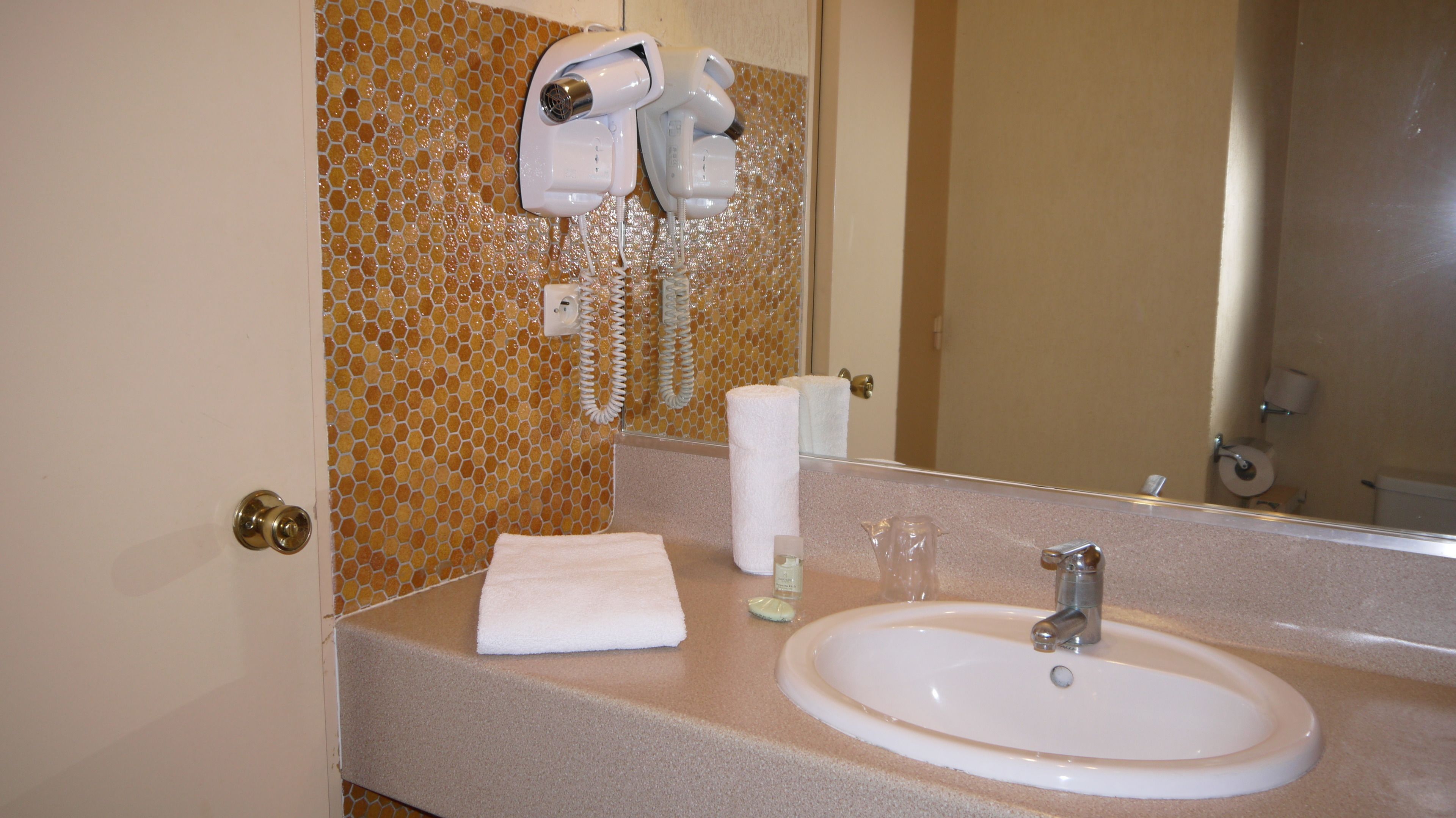 A bathroom with a sink, a towel, a hairdryer, and a mirror.