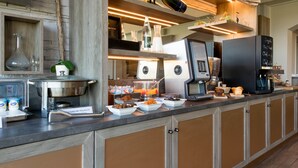 A breakfast bar with a coffee machine, a bottle of champagne, and various food items.