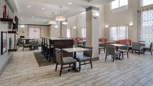 Un amplio vestíbulo de hotel con varias zonas de estar, incluyendo mesas y sillas, y una recepción.