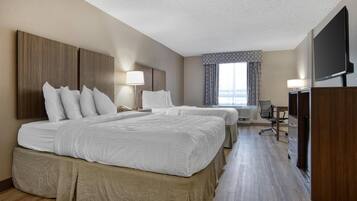 A hotel room with two beds, a desk, a chair, a TV, and a window with curtains.