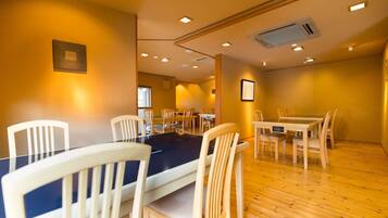A dining area with wooden tables and chairs, recessed ceiling lights, and a visible air conditioning unit.