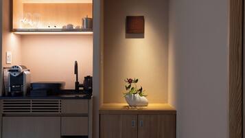 A modern kitchen with a built-in coffee machine, a kettle, and a vase with flowers on the counter.