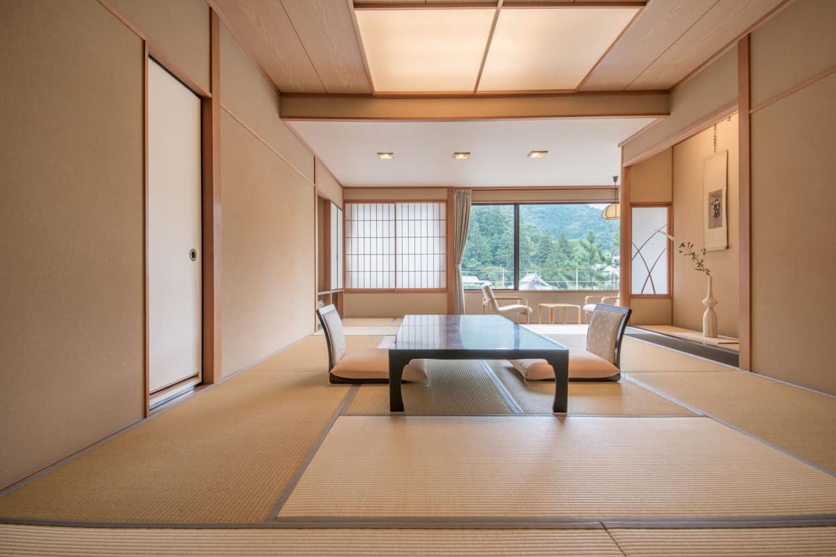 Une pièce de style japonais traditionnel, avec un sol recouvert de tatamis, une table basse et des portes coulissantes.