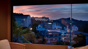 Un balcón con vistas a un paisaje urbano al anochecer, con edificios y una montaña.