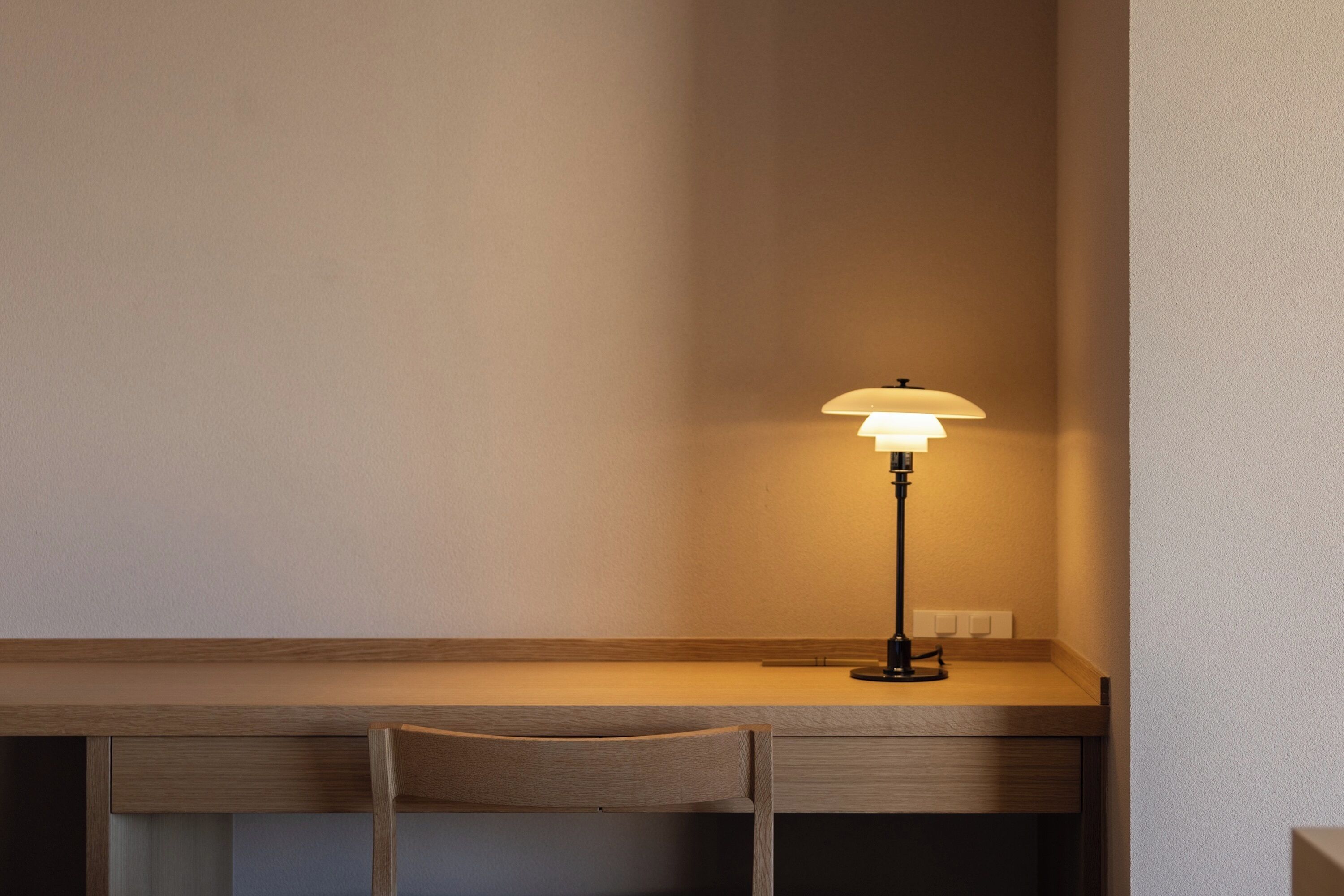 Een bureau met een lamp, een stoel en een stopcontact.