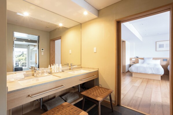 Un baño moderno con un espejo grande, lavamanos dobles y una banca.