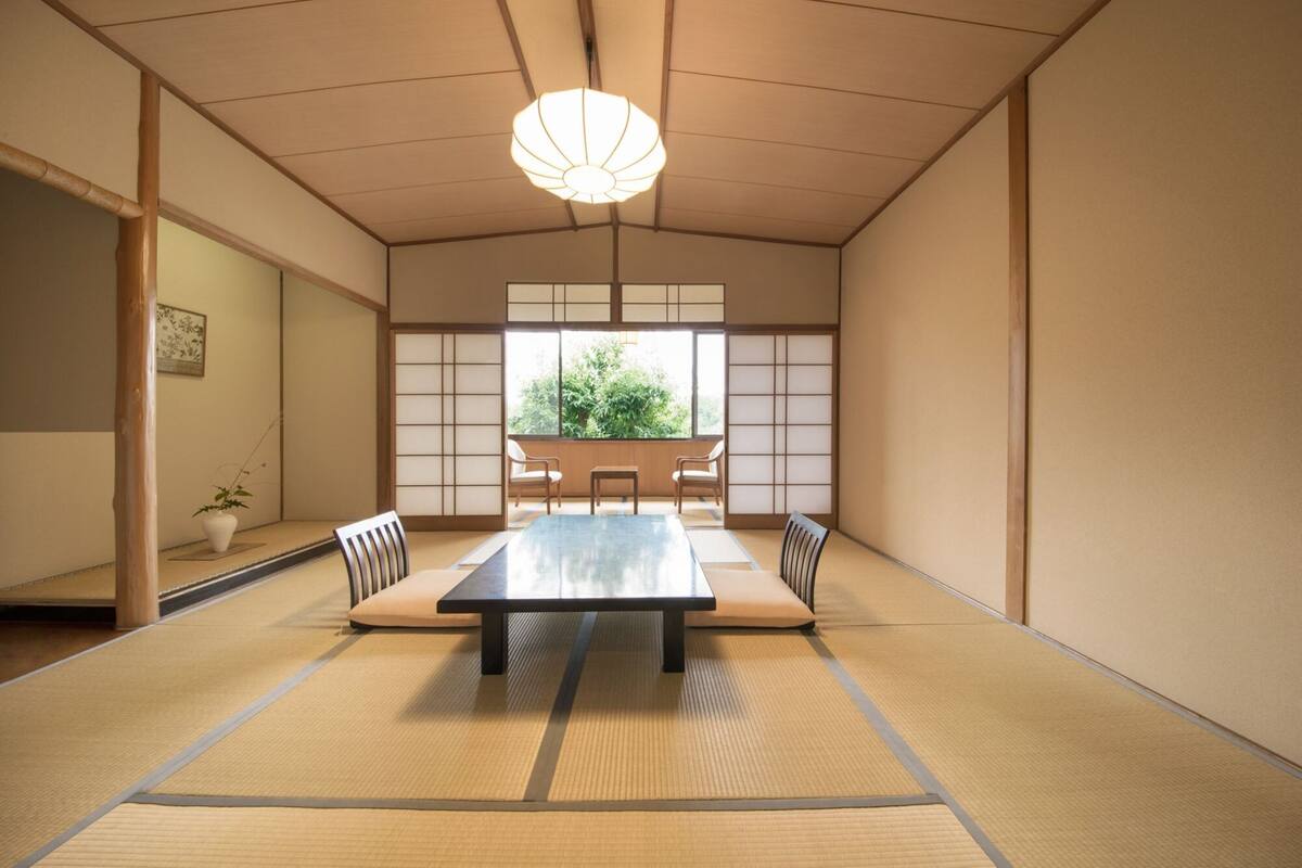 Une pièce de style japonais traditionnel, avec un sol recouvert de tatamis, une table basse et des portes coulissantes.