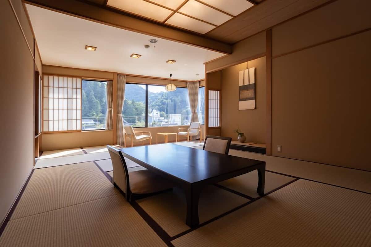 Una habitación japonesa tradicional con suelo de tatami, una mesa baja y puertas correderas.