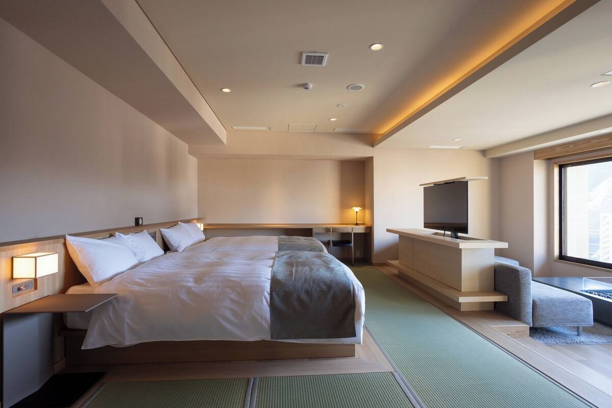 Une chambre d’hôtel moderne dotée d’un grand lit, d’un bureau, d’une télévision et offrant une vue sur la ville.