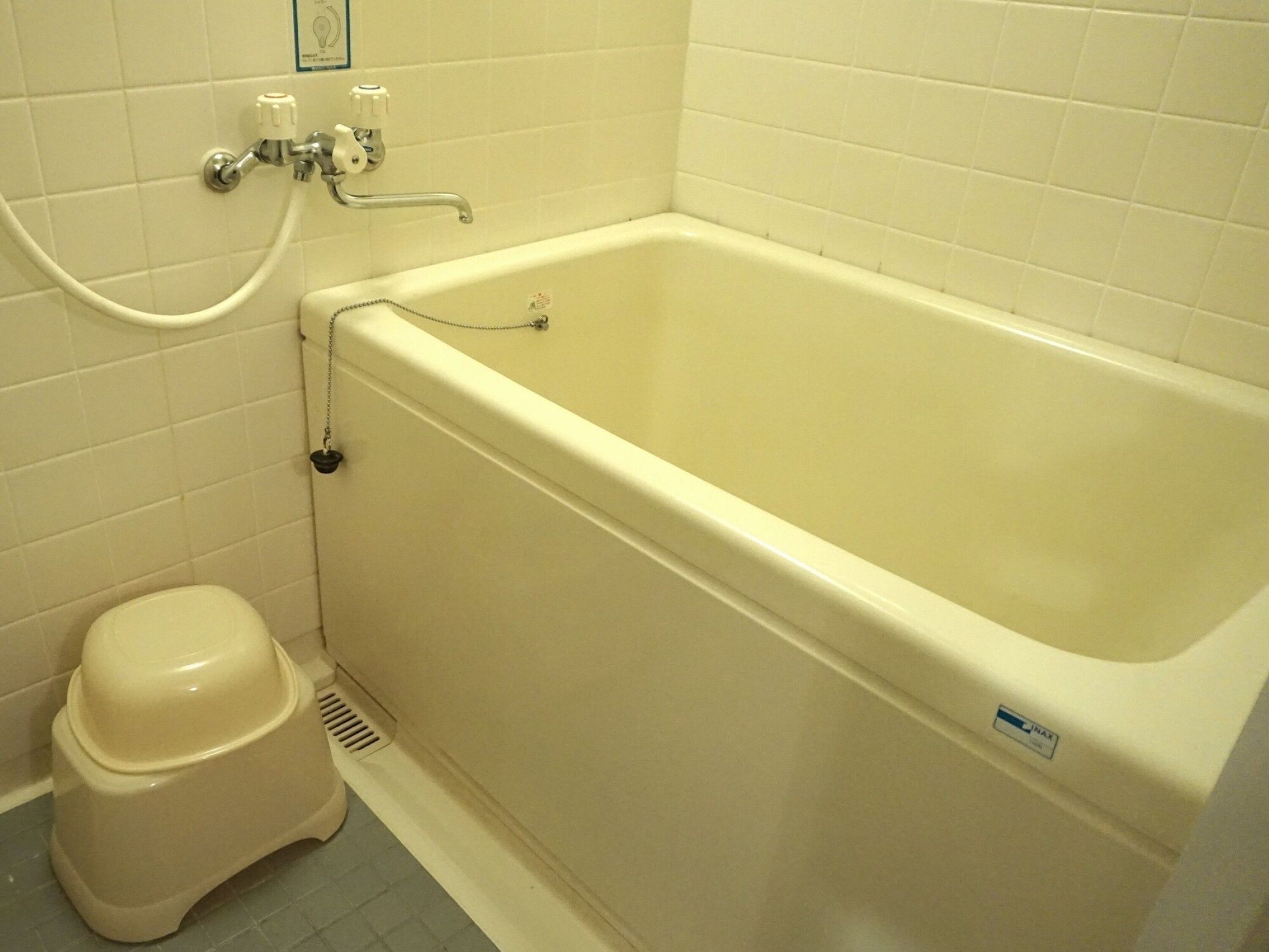 A bathroom with a bathtub, toilet, and a shower hose.