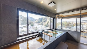 Un spa moderno con un amplio ventanal, una bañera de hidromasaje y vistas a un paisaje urbano.