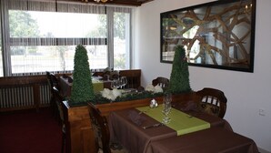 A dining area with a table set for two, a chandelier, and a large abstract painting on the wall. - Hotel de la Gare (Monthey)