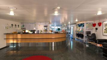 A modern reception area with a curved counter, a reception desk, and a seating area with a red rug.